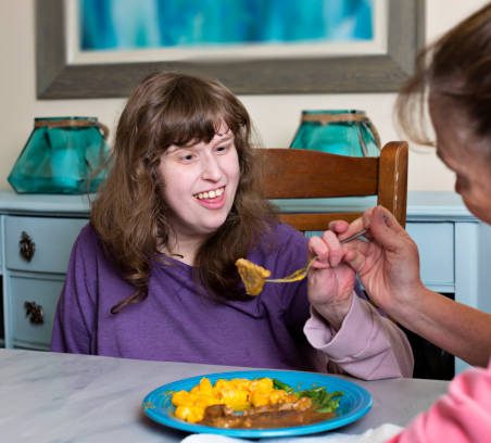 A young person being assisted with her meal routine