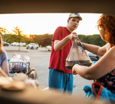 A young person assisting a woman with her shopping